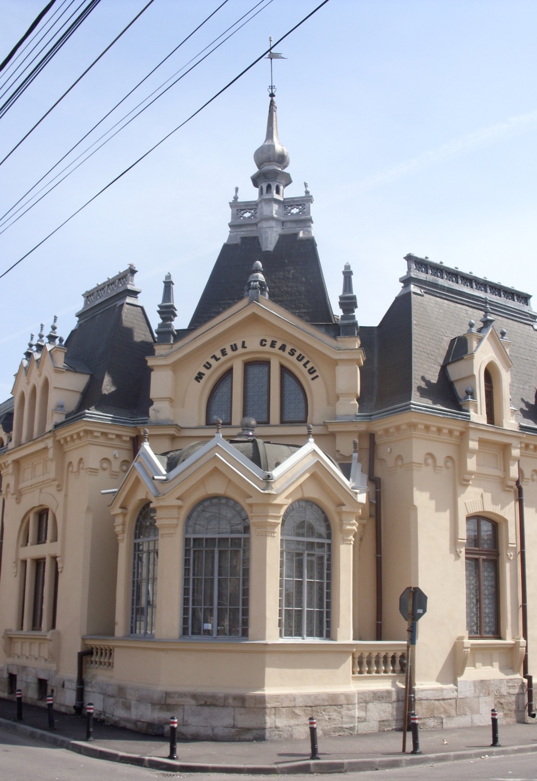 Fațada restaurată, în culoarea cremului, cu inscripția „Muzeul Ceasului” sub fronton și turnul cu săgeată