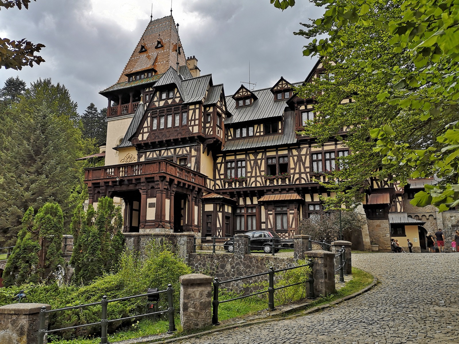 Castelul văzut de pe aleea pavată care urcă spre intrare, între copaci